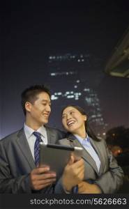 Young business people smiling and holding digital tablet