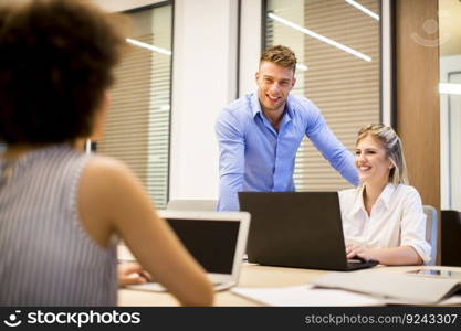 Young business people using laptop and smiling while working in office