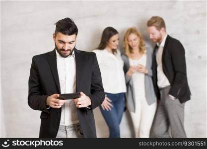 Young business people with mobile phone standing by the wall