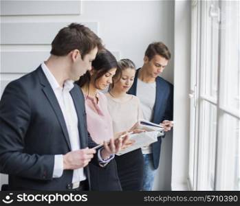 Young business people working by window in office
