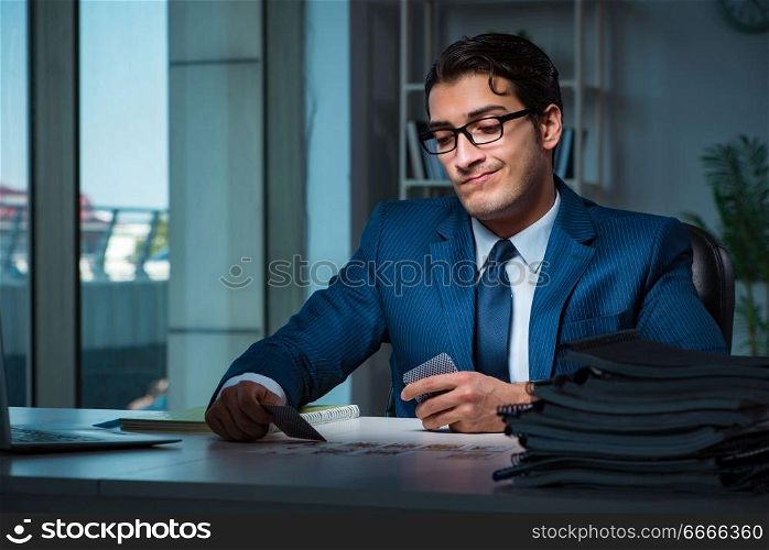 Young business playing cards late in office