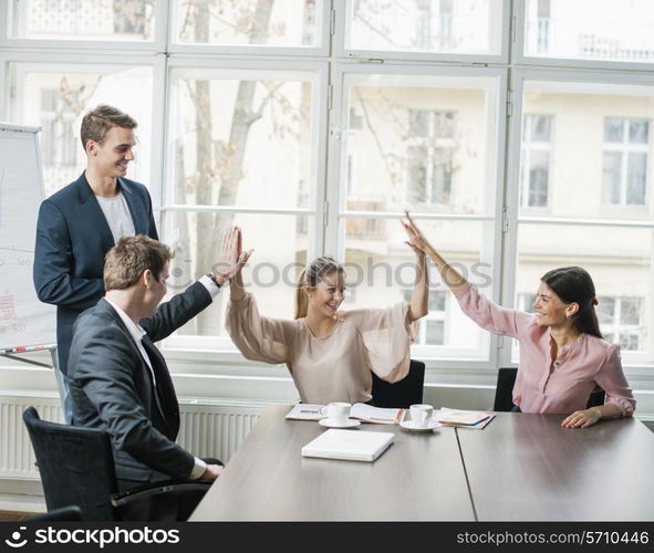 Young business team doing high five at conference table