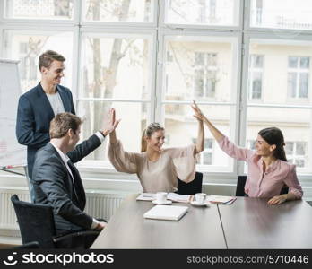 Young business team doing high five at conference table