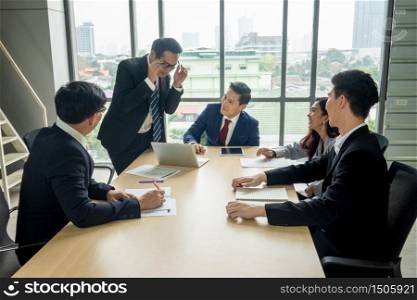 young business team working together at office. Manager pointing at a chart and explaining the analysis about business strategies. Top view shot of business hand shake