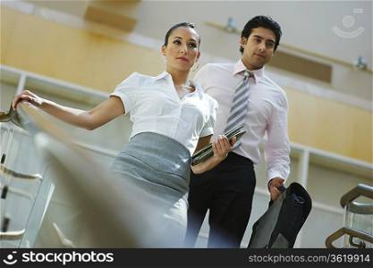 Young business woman and business man walking down stairs