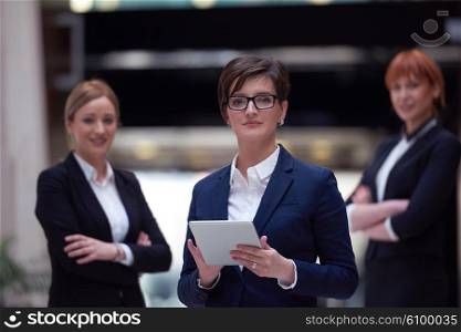 young business woman group, team standing in modern bright office and working on tablet computer