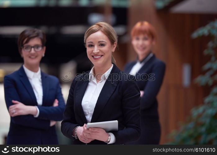 young business woman group, team standing in modern bright office and working on tablet computer