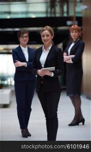young business woman group, team standing in modern bright office and working on tablet computer