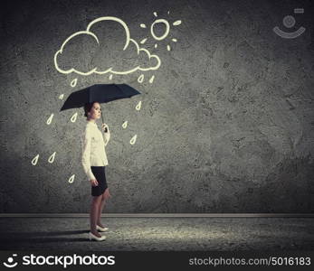 Young business woman holding an umbrella. Young business woman in suit standing and holding an umbrella