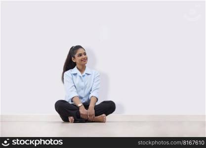 Young business woman in formal outfit sitting on floor and looking elsewhere