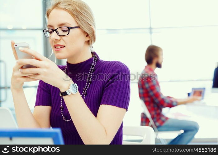 Young business woman in office holding mobile phone