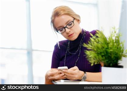 Young business woman in office holding mobile phone