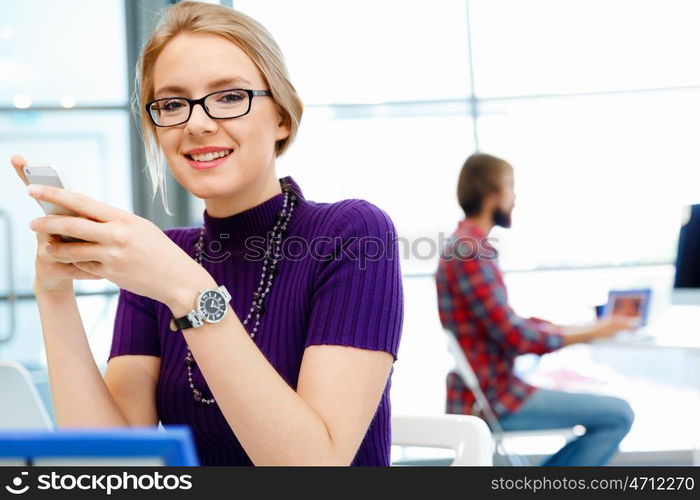 Young business woman in office holding mobile phone