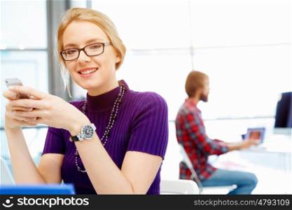Young business woman in office holding mobile phone