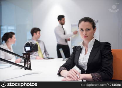 young business woman on meeting usineg laptop computer, blured group of people in background at modern bright startup office interior taking notes on white flip board and brainstorming about plans and ideas