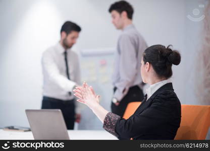 young business woman on meeting usineg laptop computer, blured group of people in background at modern bright startup office interior taking notes on white flip board and brainstorming about plans and ideas