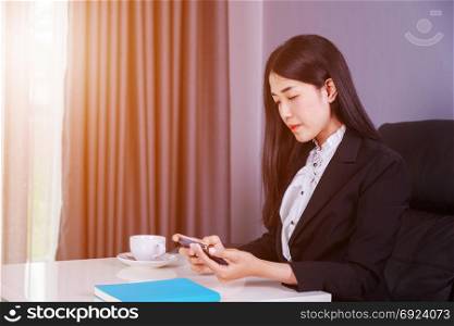 young business woman sitting at the desk and using mobile phone