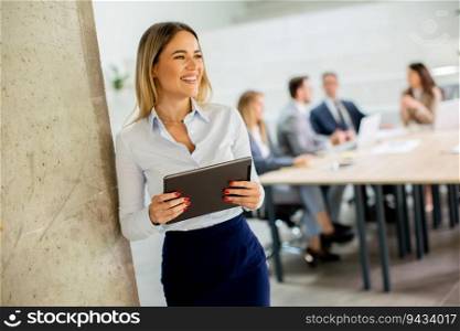 Young business woman standing with digital tablet in the office