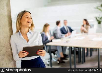 Young business woman standing with digital tablet in the office