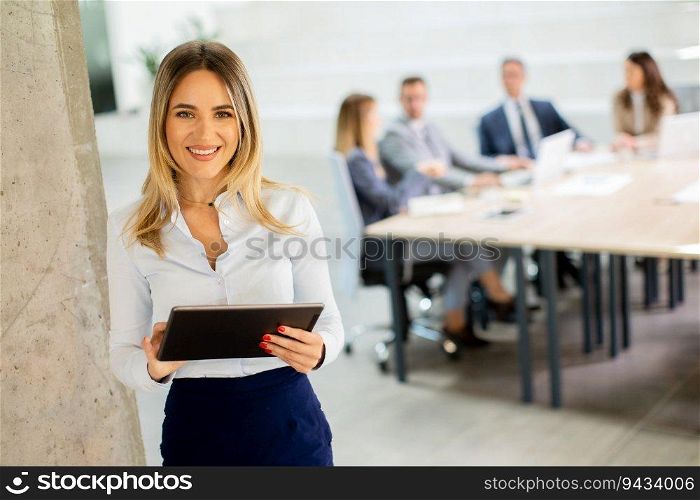 Young business woman standing with digital tablet in the office hallway