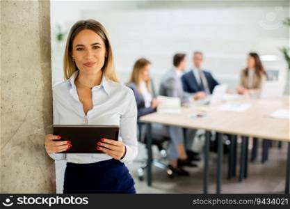 Young business woman standing with digital tablet in the office hallway