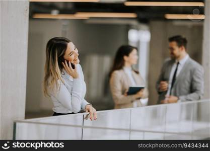 Young business woman standing with mobile phone in the office hallway