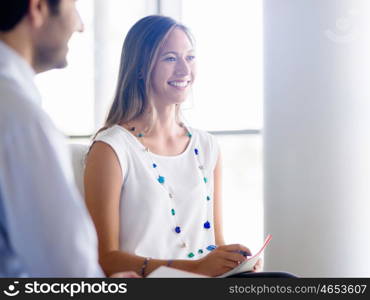 Young business woman talking to her collegue and smiling