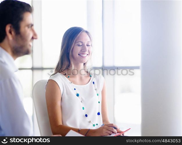 Young business woman talking to her collegue and smiling