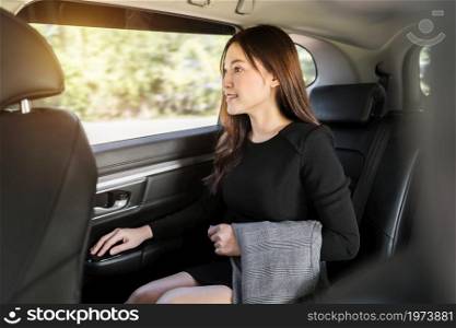 young business woman thinking and looking view out of window while sitting in the back seat of car