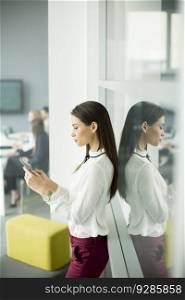 Young business woman using a mobile phone while business people sitting in office at background