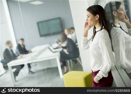 Young business woman using a mobile phone while business people sitting in office at background