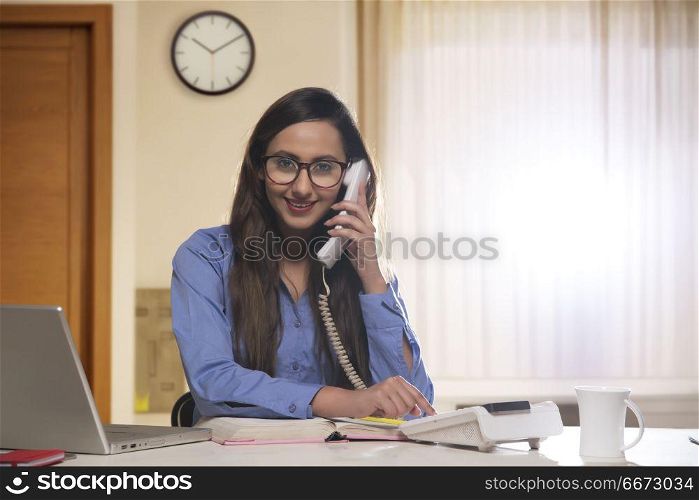 Young business woman using telephone and laptop computer