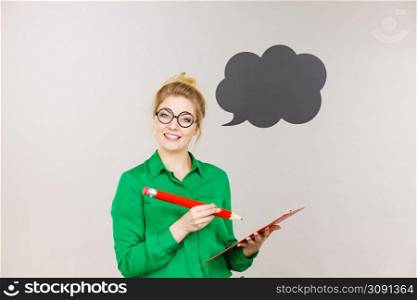 Young business woman wearing jacket intensive thinking finding great problem solution and ideas writing something down in note, black speech bubble next to her. Business woman intensive thinking and writing