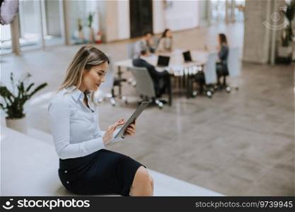Young business woman with digital tablet standing in the modern office in front of her team