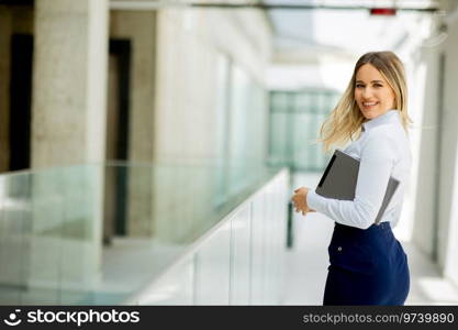 Young business woman with digital tablet standing in the modern office wallway