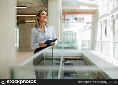 Young business woman with notebook standing in the modern office wallway