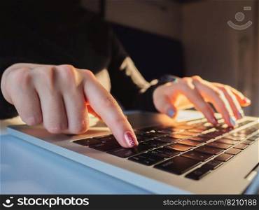 Young business woman working on laptop. Focus on hands typing on keyboard. Sunrise or sunset light leaks.. Young business woman working on laptop. Focus on hands typing on keyboard. Sunrise or sunset light leaks