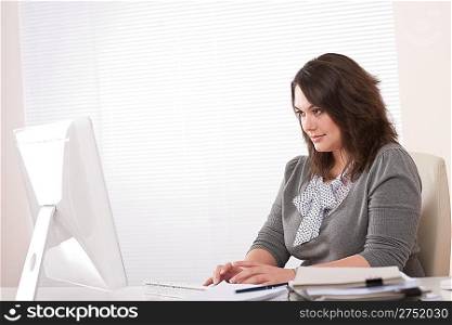 Young business woman working with computer at office sitting at desk