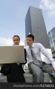 Young businesscouple sat with laptop in city centre