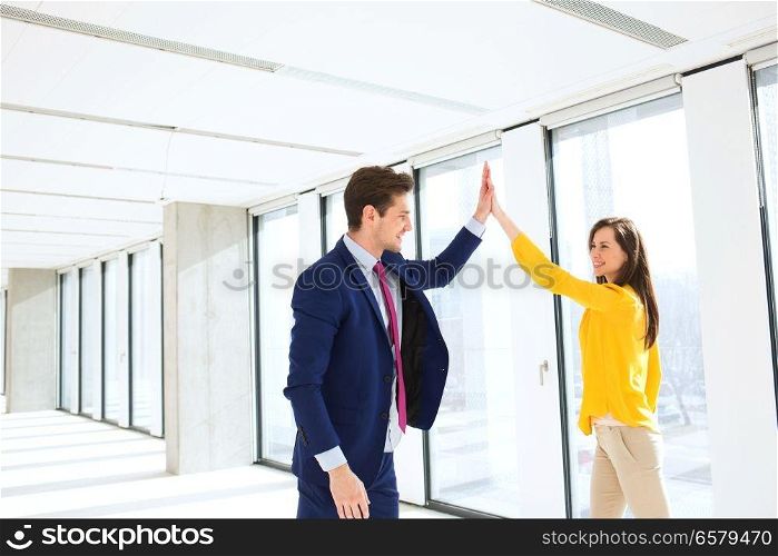 Young businessman and businesswoman high fiving in new office