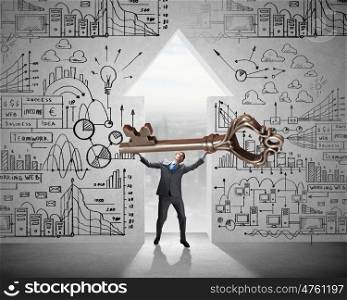 Young businessman and keyhole at background lifting big key above head. Find key to success