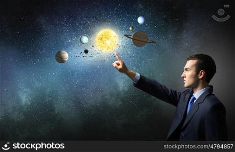 Young businessman and planets of space spinning around. Man exploring space