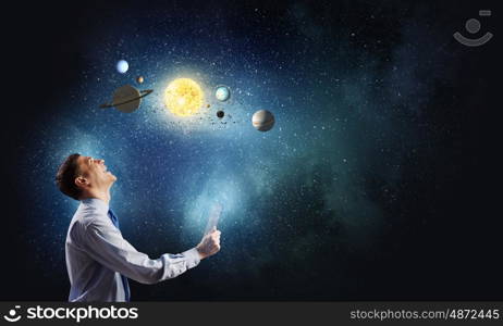 Young businessman and planets of space spinning around. Man exploring space