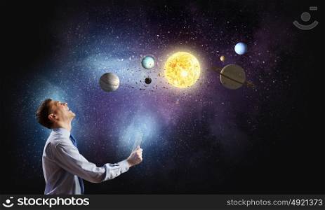 Young businessman and planets of space spinning around. Man exploring space
