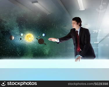 Young businessman and planets of space spinning around. Man exploring space