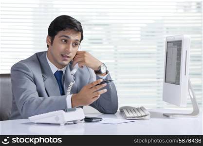 Young businessman answering telephone at office desk