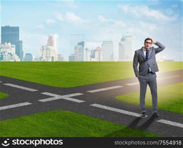 Young businessman at crossroads in uncertainty concept. The young businessman at crossroads in uncertainty concept