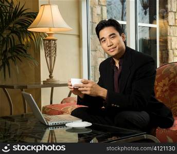 Young Businessman at Laptop Holding a Coffee Cup