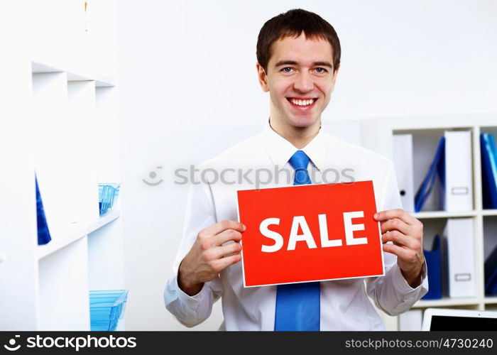 Young businessman at work in office with sale sign