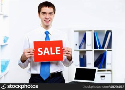 Young businessman at work in office with sale sign